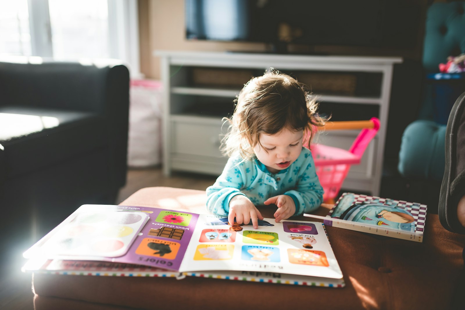 Criança pequena explorando um livro infantil colorido