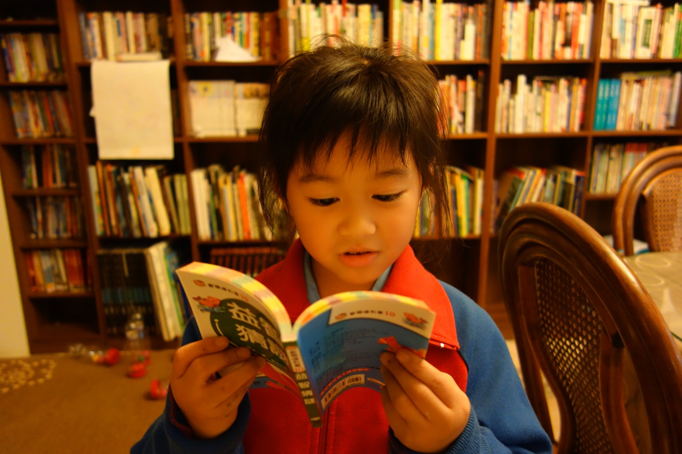 Menina folheando um livro infantil sentada em casa