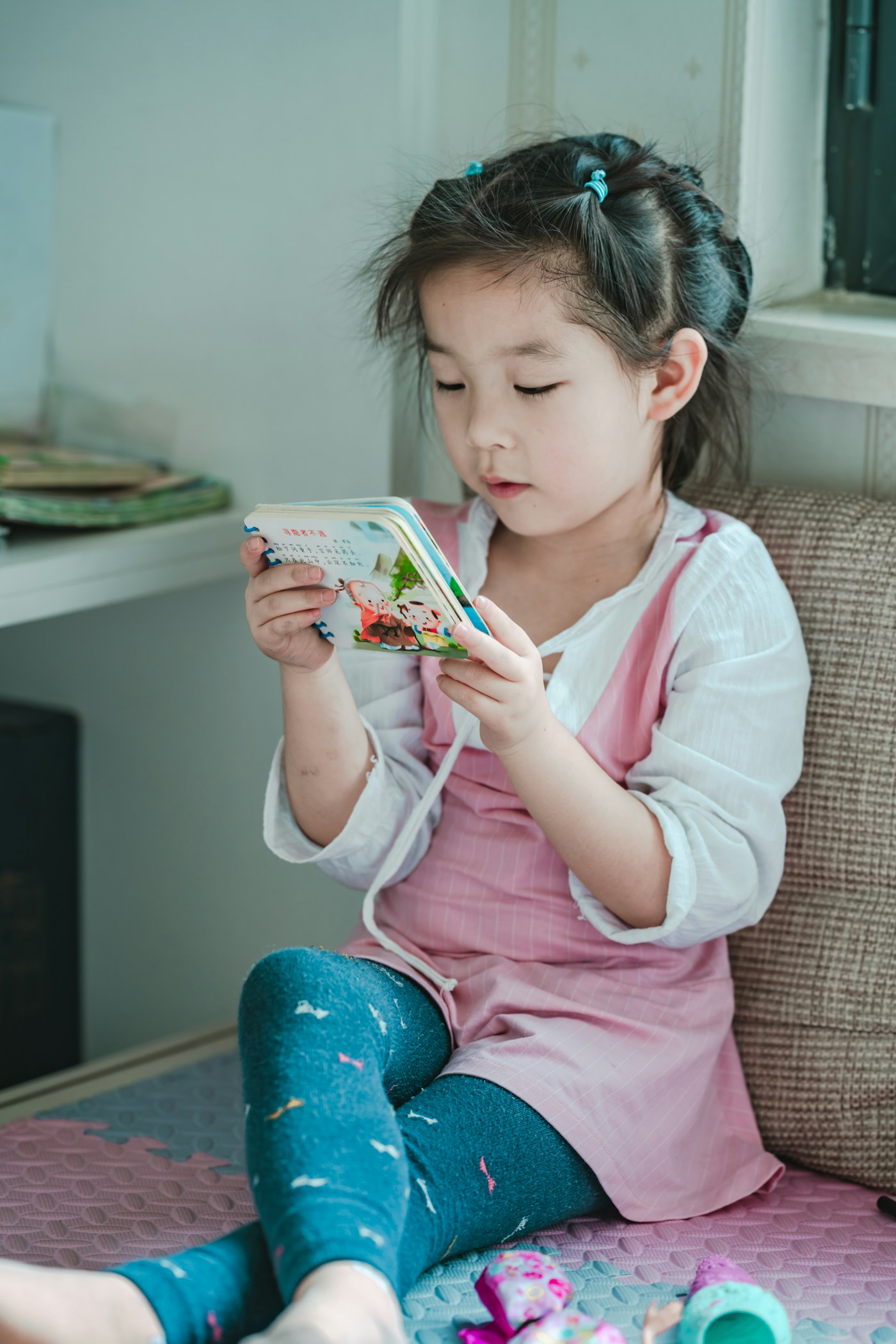 Menina sentada lendo um livro infantil