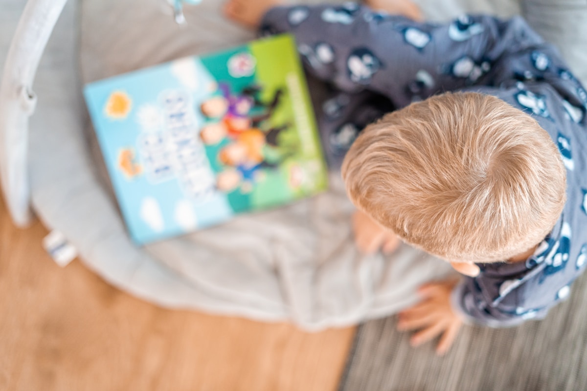 Menino lendo um livro deitado em um ambiente aconchegante